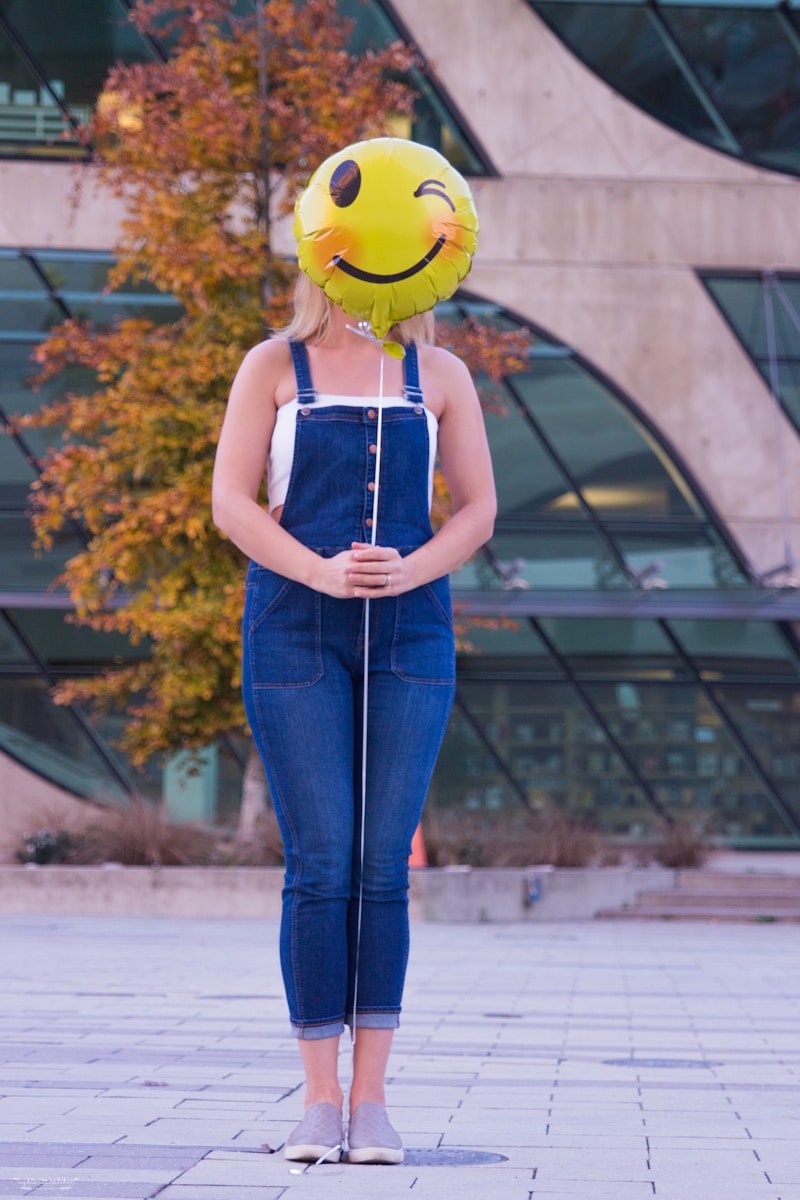 Photo by Partho Chakraborty woman in blue denim jeans with yellow hat standing near brown leaf trees during daytime